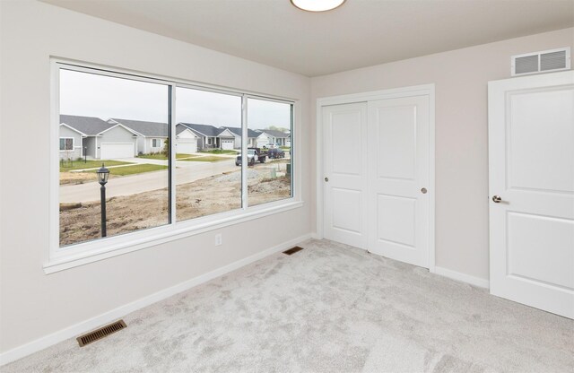 unfurnished bedroom with a closet, carpet, visible vents, and baseboards
