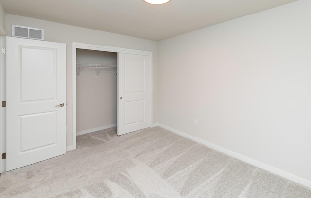 unfurnished bedroom featuring a closet, visible vents, baseboards, and light carpet