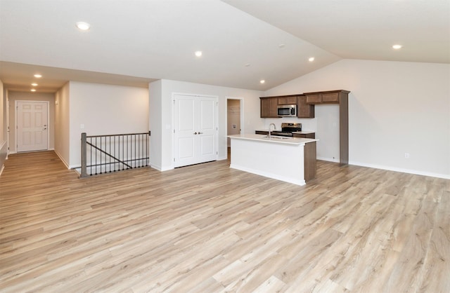 kitchen with light wood finished floors, appliances with stainless steel finishes, and a kitchen island with sink