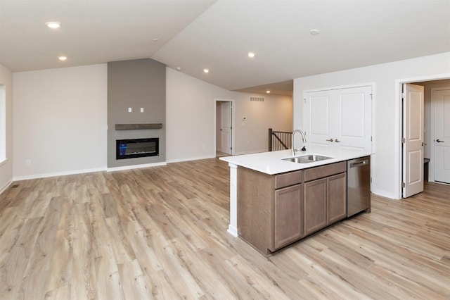 kitchen featuring light countertops, dishwasher, a sink, light wood-style floors, and a center island with sink