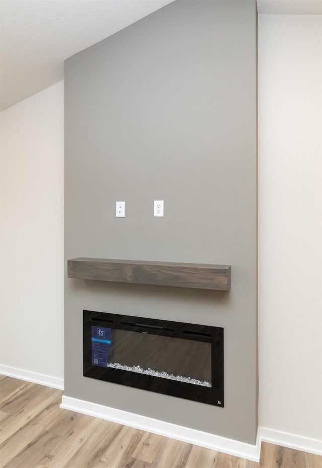 interior details featuring baseboards, wood finished floors, and a glass covered fireplace