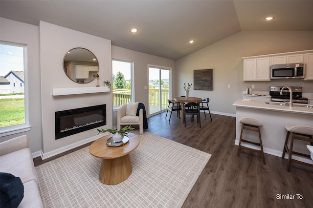 6443 NE 11th Ct, Des Moines, IA 50313 - living area featuring vaulted ceiling, a glass covered fireplace, baseboards, dark wood finished floors, and recessed lighting