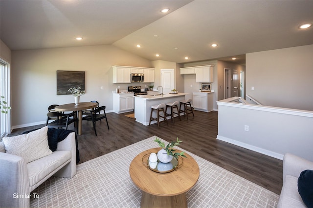 living room featuring vaulted ceiling, sink, and dark hardwood / wood-style floors