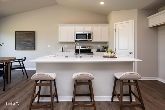 6443 NE 11th Ct, Des Moines, IA 50313 - kitchen with appliances with stainless steel finishes, a sink, white cabinetry, a kitchen breakfast bar, and vaulted ceiling