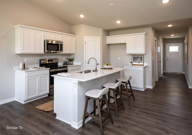 kitchen featuring sink, a kitchen island with sink, stainless steel appliances, white cabinets, and a kitchen bar