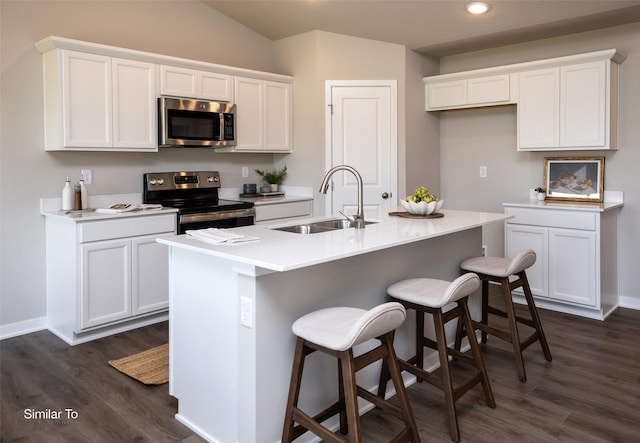 kitchen featuring sink, white cabinetry, stainless steel appliances, an island with sink, and a kitchen bar