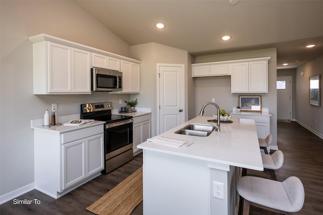 kitchen featuring sink, appliances with stainless steel finishes, an island with sink, white cabinets, and a kitchen bar