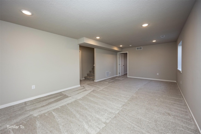 6443 NE 11th Ct, Des Moines, IA 50313 - empty room with light carpet, stairs, baseboards, recessed lighting, and a textured ceiling