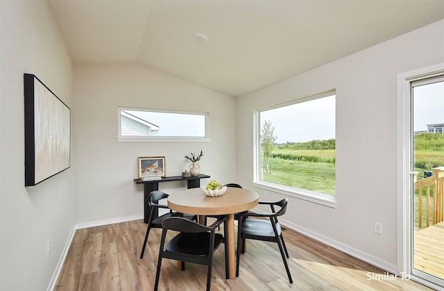 dining space with a healthy amount of sunlight, vaulted ceiling, and light hardwood / wood-style flooring