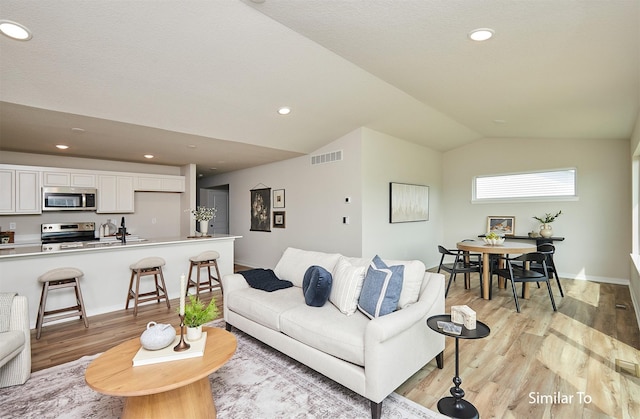 living room featuring vaulted ceiling and light hardwood / wood-style floors