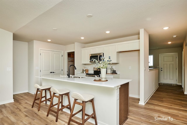 kitchen featuring white cabinetry, appliances with stainless steel finishes, sink, and a center island with sink