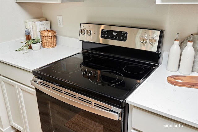 kitchen with electric stove and white cabinets