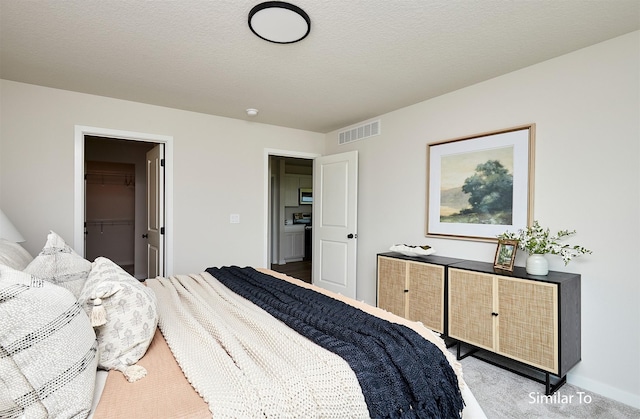 carpeted bedroom with a spacious closet and a textured ceiling