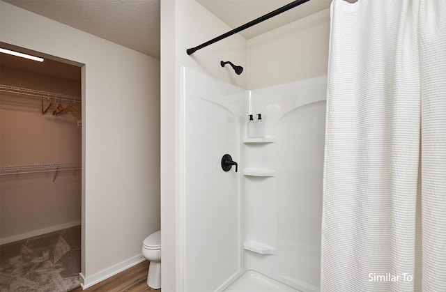 bathroom with curtained shower, toilet, and a textured ceiling