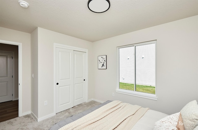 carpeted bedroom with a textured ceiling and a closet