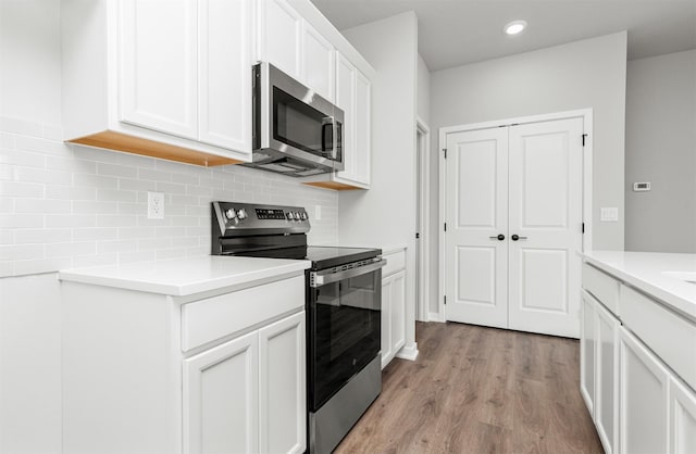 6423 NE 11th Ct, Des Moines, IA 50313 - kitchen with stainless steel appliances, decorative backsplash, light wood-style flooring, light countertops, and white cabinetry