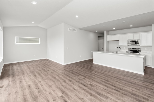 6423 NE 11th Ct, Des Moines, IA 50313 - unfurnished living room with a sink, lofted ceiling, recessed lighting, light wood-type flooring, and baseboards