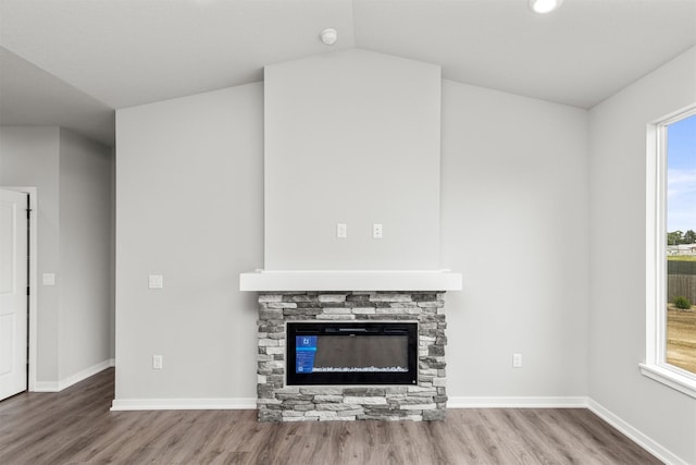 6423 NE 11th Ct, Des Moines, IA 50313 - unfurnished living room with wood finished floors, baseboards, a fireplace, and lofted ceiling