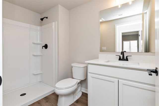 6423 NE 11th Ct, Des Moines, IA 50313 - full bathroom featuring wood finished floors, vanity, toilet, a shower, and baseboards