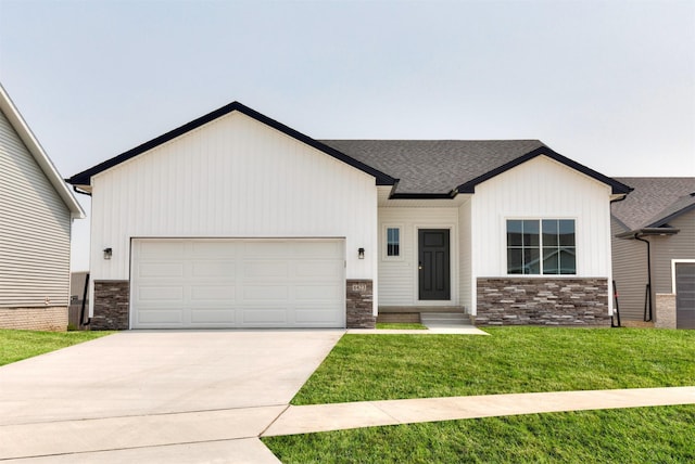 6423 NE 11th Ct, Des Moines, IA 50313 - view of front of home with stone siding, an attached garage, concrete driveway, a front yard, and a shingled roof