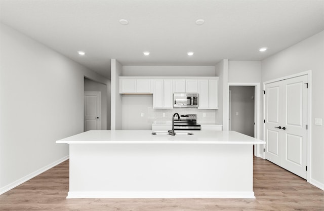 6423 NE 11th Ct, Des Moines, IA 50313 - kitchen with stainless steel appliances, a sink, an island with sink, white cabinets, and recessed lighting