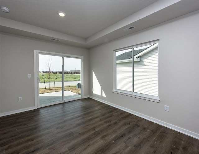 unfurnished room featuring baseboards, visible vents, dark wood-style floors, and recessed lighting