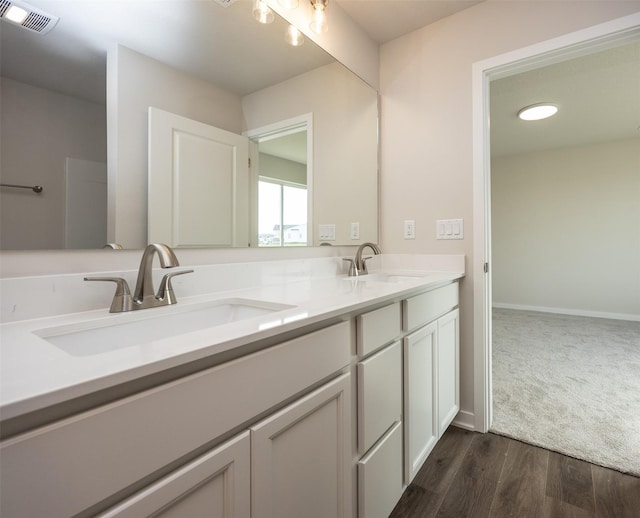 full bathroom featuring double vanity, visible vents, wood finished floors, and a sink