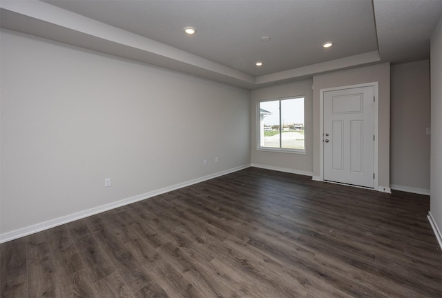 spare room with baseboards, recessed lighting, a raised ceiling, and dark wood finished floors