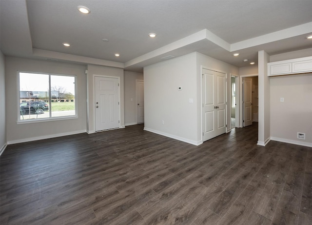 unfurnished living room with recessed lighting, a raised ceiling, baseboards, and dark wood-style floors