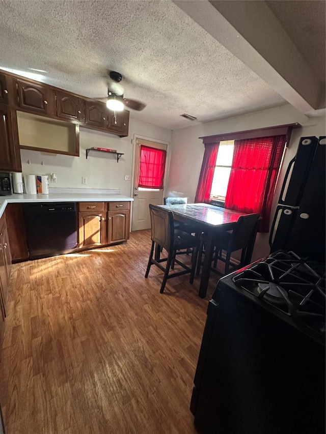 dining space with ceiling fan, a textured ceiling, and light hardwood / wood-style floors