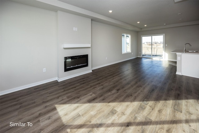 unfurnished living room with sink and dark wood-type flooring