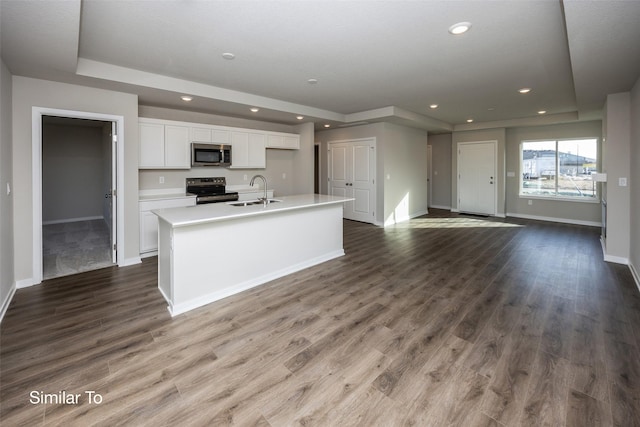 kitchen with dark wood-type flooring, appliances with stainless steel finishes, an island with sink, and white cabinets