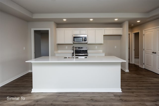 kitchen with white cabinetry, dark hardwood / wood-style flooring, an island with sink, and appliances with stainless steel finishes