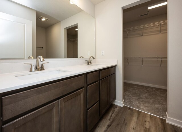 2228 Legacy Dr, Norwalk, IA 50211 - bathroom with wood finished floors, double vanity, a walk in closet, and baseboards