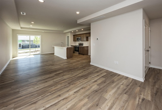 2228 Legacy Dr, Norwalk, IA 50211 - unfurnished living room featuring recessed lighting, a sink, a raised ceiling, dark wood-style floors, and baseboards
