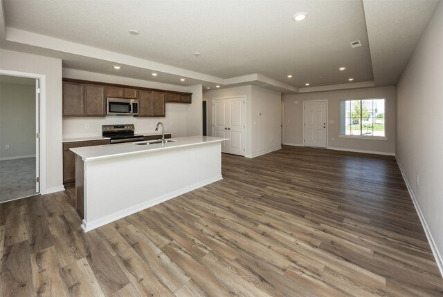 2228 Legacy Dr, Norwalk, IA 50211 - kitchen with appliances with stainless steel finishes, a sink, baseboards, wood finished floors, and an island with sink