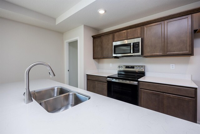2228 Legacy Dr, Norwalk, IA 50211 - kitchen featuring stainless steel appliances, a sink, dark brown cabinets, and recessed lighting