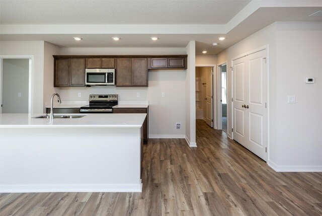 2228 Legacy Dr, Norwalk, IA 50211 - kitchen with stainless steel appliances, a sink, light wood-style flooring, baseboards, and light countertops