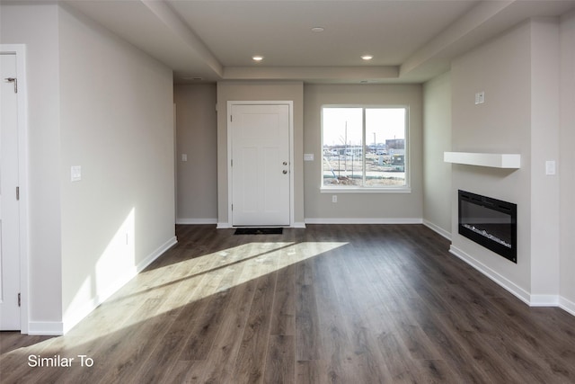 unfurnished living room featuring dark wood-style flooring, recessed lighting, a glass covered fireplace, and baseboards