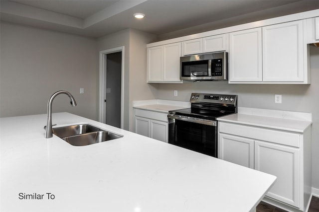 kitchen featuring appliances with stainless steel finishes, light countertops, white cabinetry, a sink, and recessed lighting