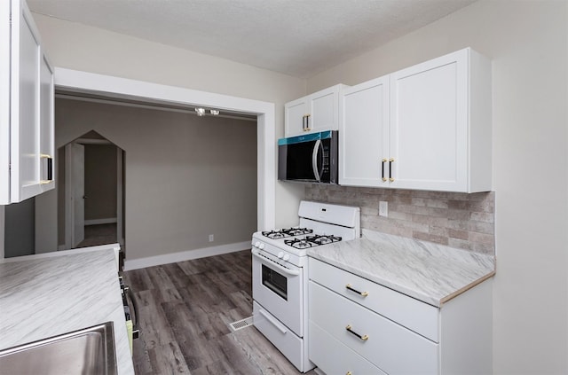 kitchen with sink, dark hardwood / wood-style floors, white cabinets, white gas range, and decorative backsplash