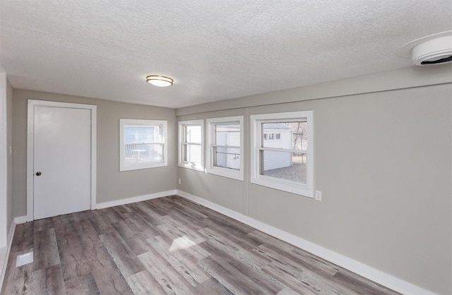 spare room featuring hardwood / wood-style floors and a textured ceiling