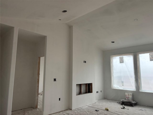 unfurnished living room featuring a wealth of natural light and vaulted ceiling