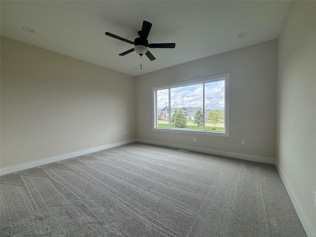 carpeted spare room featuring baseboards and ceiling fan