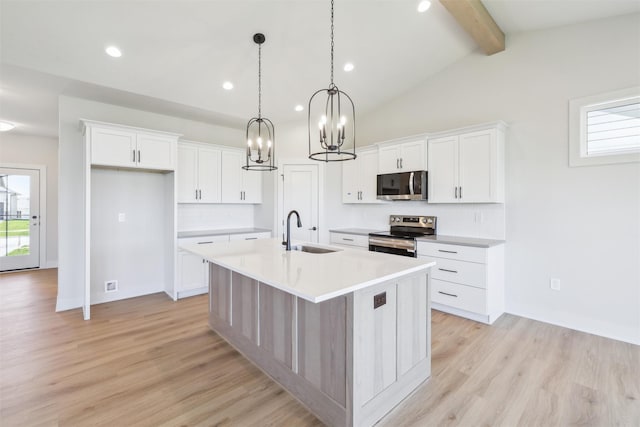 kitchen with stainless steel appliances, a sink, a center island with sink, light wood finished floors, and a chandelier