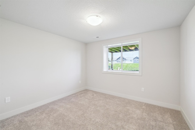 spare room featuring carpet, baseboards, and a textured ceiling