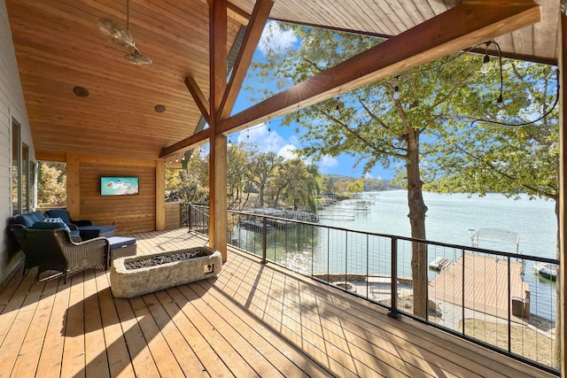 wooden terrace featuring an outdoor living space with a fire pit and a water view