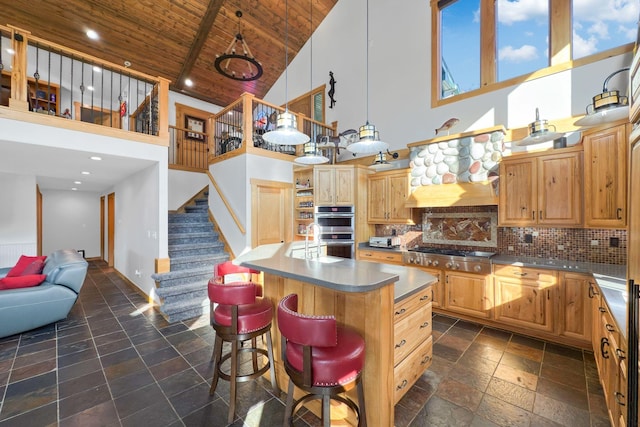 kitchen with a breakfast bar, stainless steel appliances, a kitchen island, decorative backsplash, and wooden ceiling