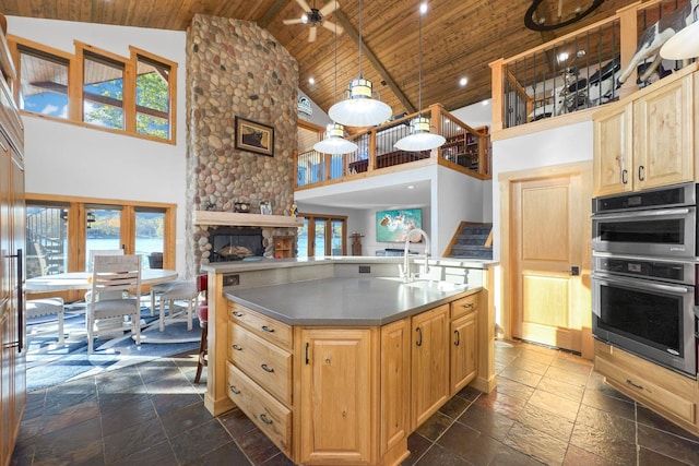 kitchen with stainless steel double oven, sink, light brown cabinets, and wooden ceiling