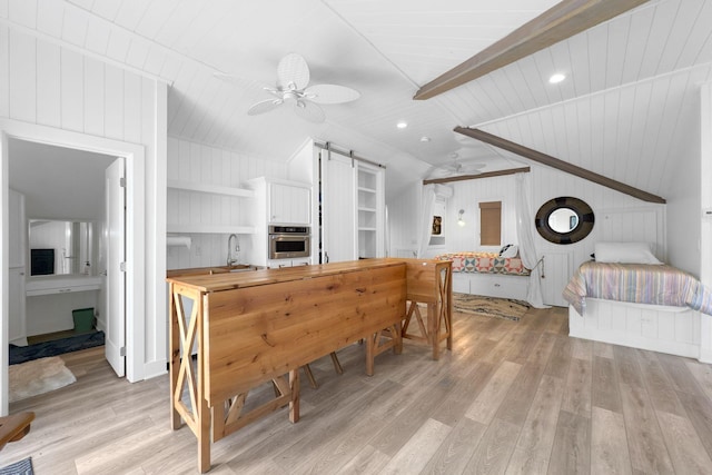 kitchen with white cabinets, a barn door, stainless steel oven, and ceiling fan